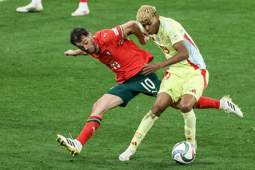 Lamine Yamal (de amarillo) comandará el ataque español a sus 18 años. Aquí pelea un balón con Bernardo Silva. (Foto: AFP)