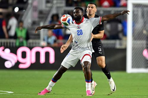 El delantero haitiano Frantzdy Pierrot y el defensa neozelandés Michael Boxall, luchan por el balón.