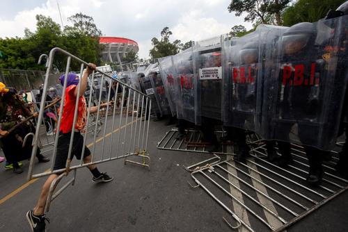 Manifestantes retiraron las vallas colocadas y se las lanzaron a las fuerzas de seguridad que custodiaban en las afueras del Estadio Ciudad de México. (Foto: AFP)