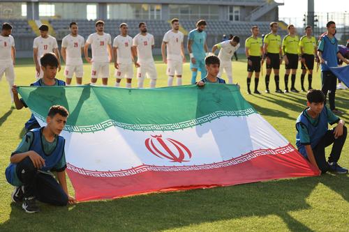 Los jugadores de Irán se colocan detrás de la bandera antes de un partido amistoso entre Irán y Gambia.