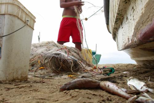 Un pescador sostiene una red en la comuna San Pedro, en Santa Elena, Ecuador con apenas algunos peces conseguidos. (Foto: AFP)