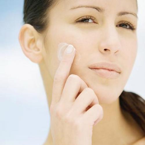 Una mujer aplica crema hidratante sobre su rostro