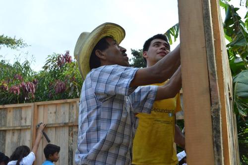 Vecino y voluntario levantan la pared de una vivienda