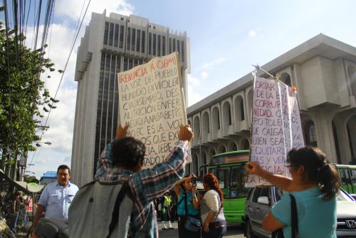 Dos manifestantes levantaron pancartas exigiendo la renuncia de Otto Pérez y se mostraron indignados con el despliegue de seguridad. "Solo en este país, la policía cuida a los ladrones", dijo la mujer. (Foto: Alexis Batres/Soy502)
