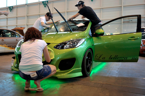 Si la superficie de la laca transparente que cubre el color del vehículo se mantiene lisa y sin rayas, el brillo se mantiene. En la imagen unos jóvenes limpian la carrocería de su coche. (Foto: EFE)