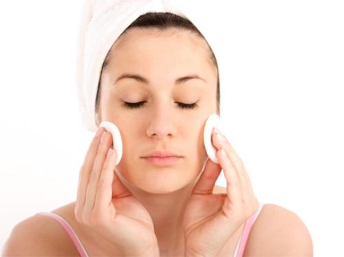 Una mujer usa algodones para tonificar sus mejillas