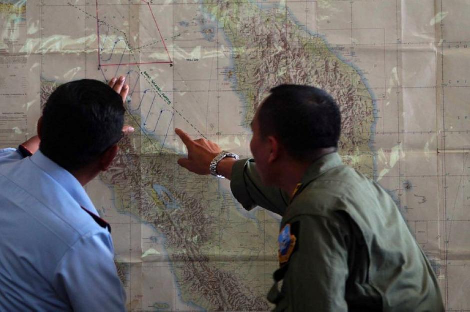 Oficiales de la Fuerza Aérea de Meda revisan el mapa de los lugares donde se ha buscado al avión desaparecido desde el sábado. (Foto:AFP)