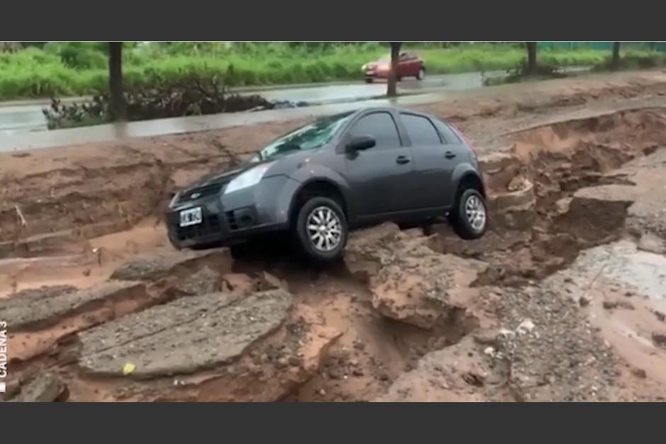 El conductor y su familia no pudieron evitar que el carro se quedara atascado en medio de la grieta provocada por las lluvias. (Captura video)