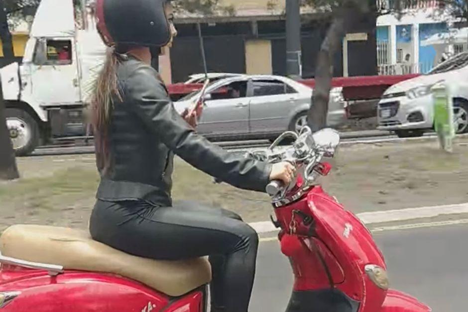 El taxista graba con su celular a una mujer en moto que también usa el celular mientras conduce. (Foto: captura video) 