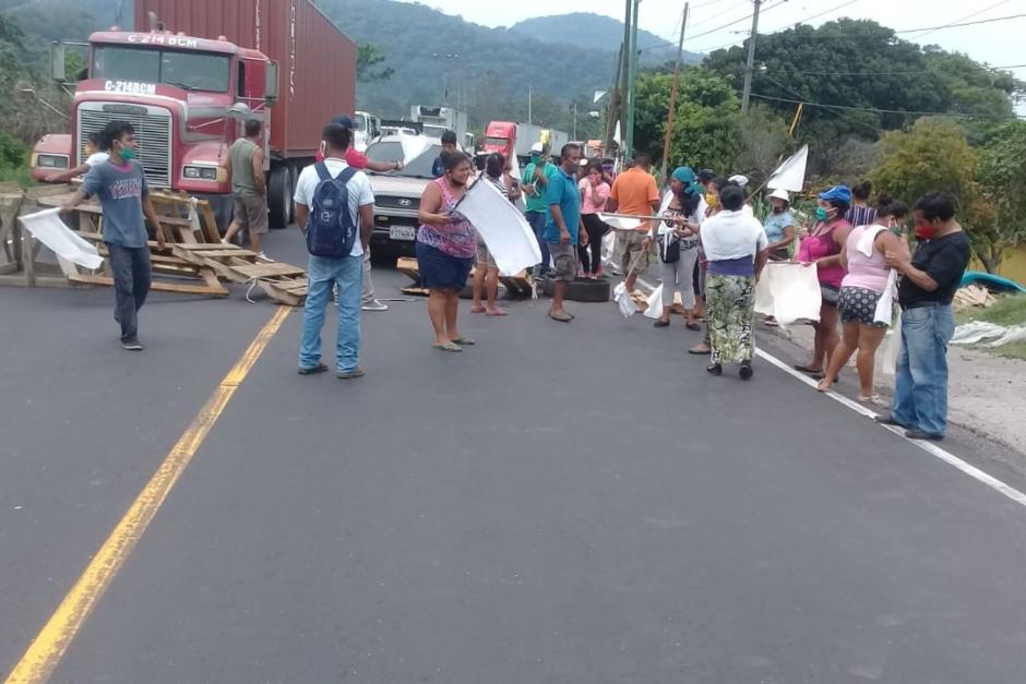 Con banderas blancas, un grupo de personas bloqueó la ruta al Pacífico en el área de "Balcones" en Palín, Escuintla. (Foto: Canal 46 News) 