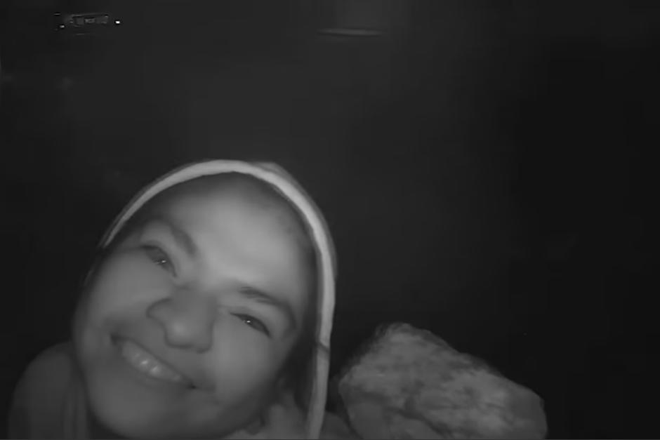 La mujer sonríe mientras sostiene una piedra con la que destruye la cámara de videovigilancia. (Captura Pantalla)