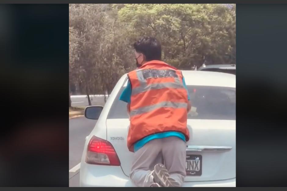 Un hombre fue captado sobre el baúl de un carro en zona 13. (Foto: captura de pantalla) 