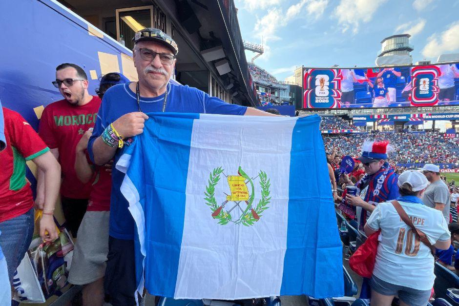 Don Carlos con una boina con pines de los Mundiales a los que ha asistido, las pulseras de todos los juegos a los que fue en Unidos 2026 y la bandera de Guatemala. (Foto: Rudy Martínez)