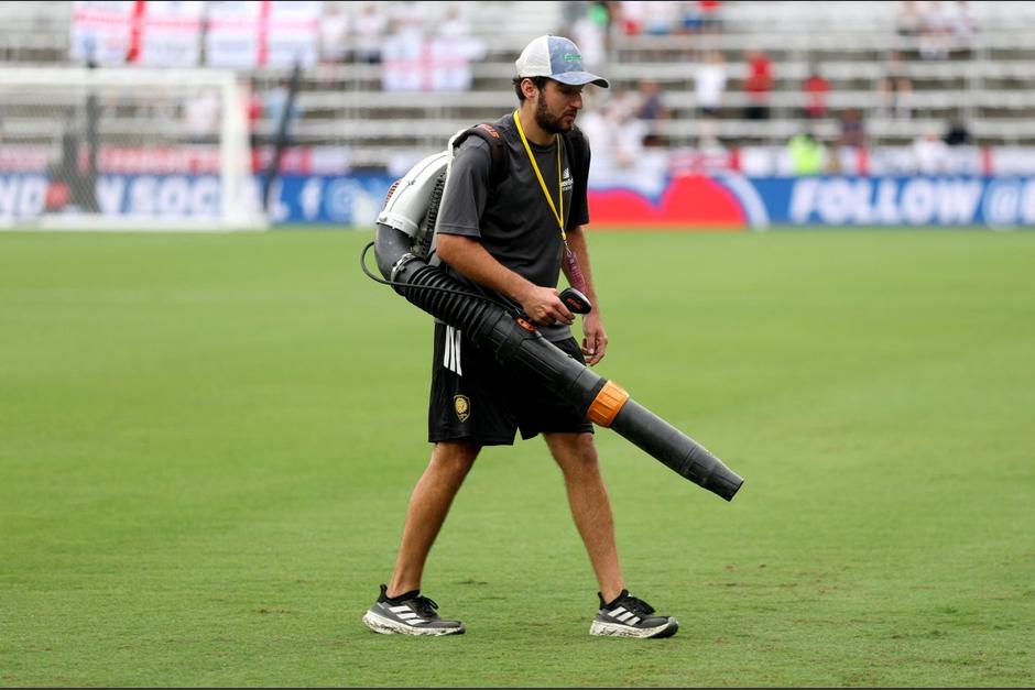 Un miembro del personal de mantenimiento seca el césped tras las fuertes lluvias previas al partido amistoso internacional entre Inglaterra y Costa Rica en el Estadio Inter&Co. (Foto: AFP)