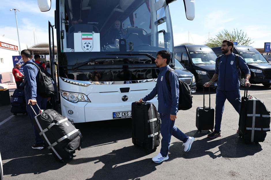 Integrantes de la selección nacional de futbol de Irán caminan con sus maletas para abordar un bus tras su llegada a Turquía.