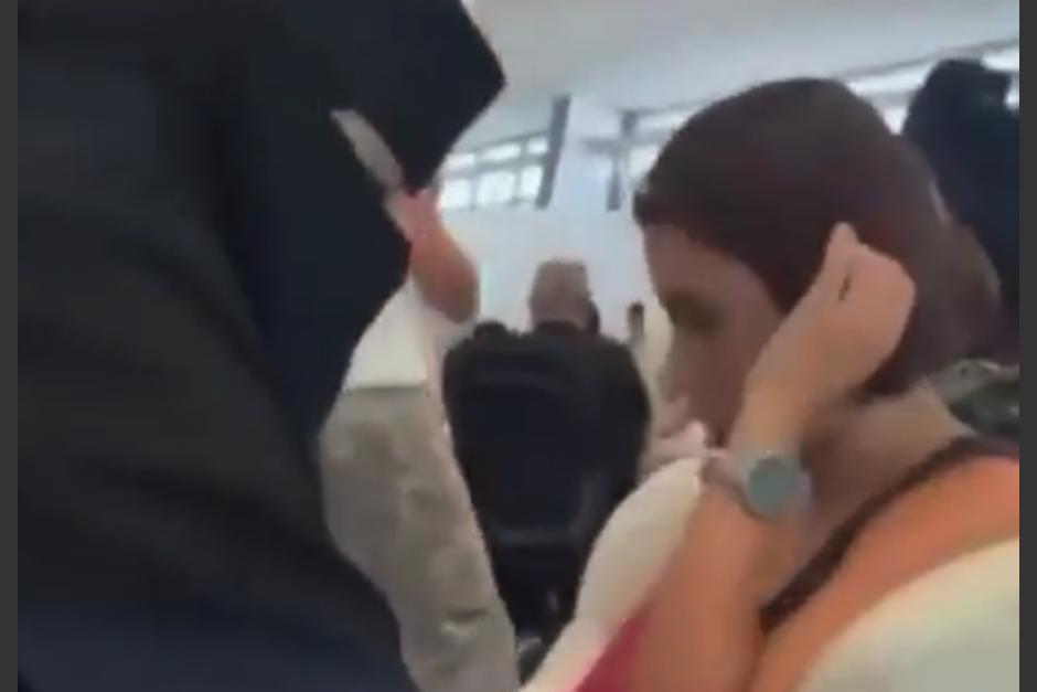 La auxiliar, que viste niqab negro, le toma la presión a la pasajera y luego habla con ella. (Foto: captura de video)