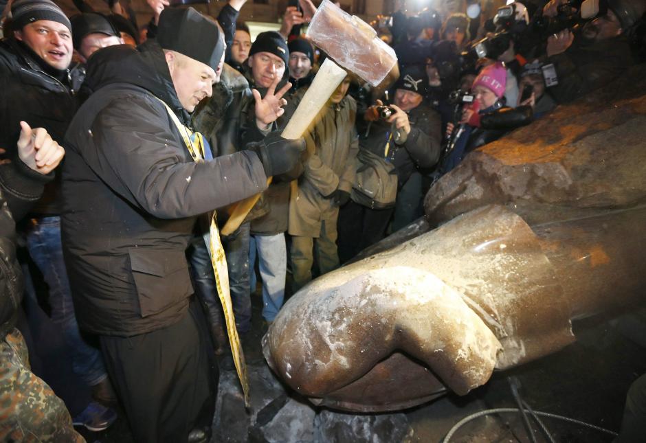 Un hombre golpea y destroza con un martillo la estatua del líder soviético Vladimir Lenin durante las protestas en Kiev, Ucrania. (Foto: EFE)