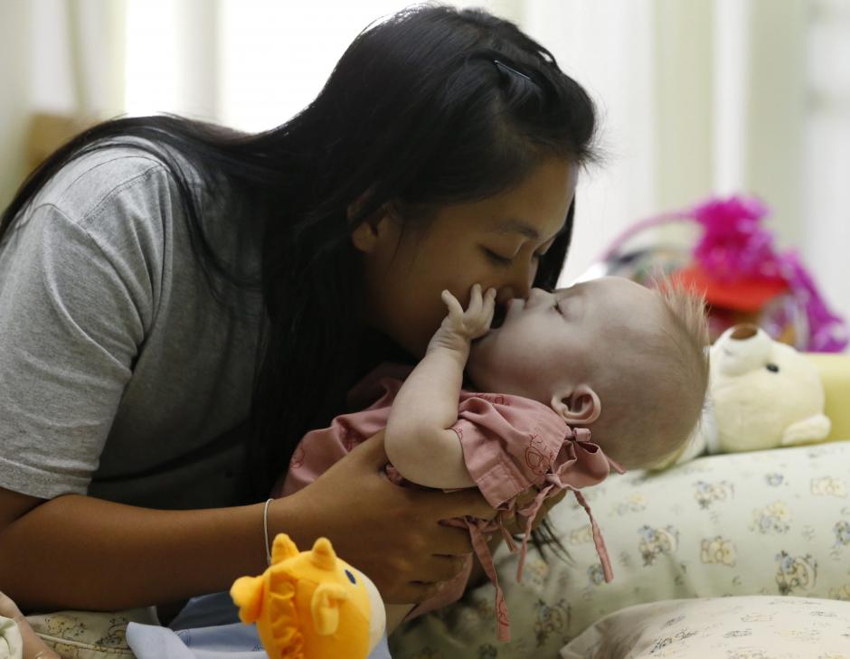 Pattharaomon Janbua, de 21 años, besa a su hijo biológico con síndrome de Down Gammy, de siete meses, en un hospital de la provincia de Chonburi (Tailandia). (Foto: EFE)