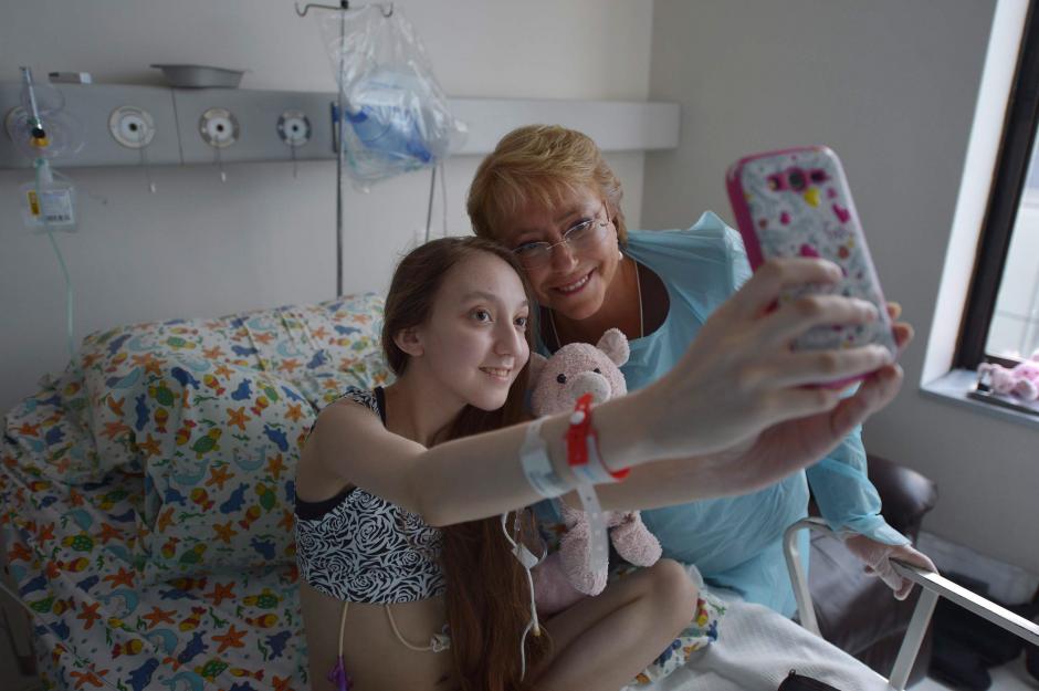  Michelle Bachelet, mientras se toma una fotografía con Valentina Maureira, la joven de 14 años que padece fibrosis quística y que pidió en un vídeo a la mandataria autorización para morir. (Foto: EFE)