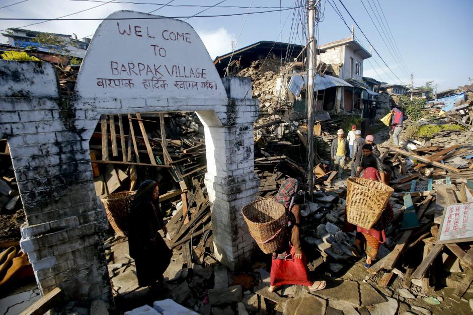 Mujeres pasan a través de un arco de bienvenida de los visitantes, por los escombros de sus casas en la aldea de Barpak, distrito de Gorkha, epicentro del terremoto que azotó Nepal. (Foto:EFE/DIEGO AZUBEL)
