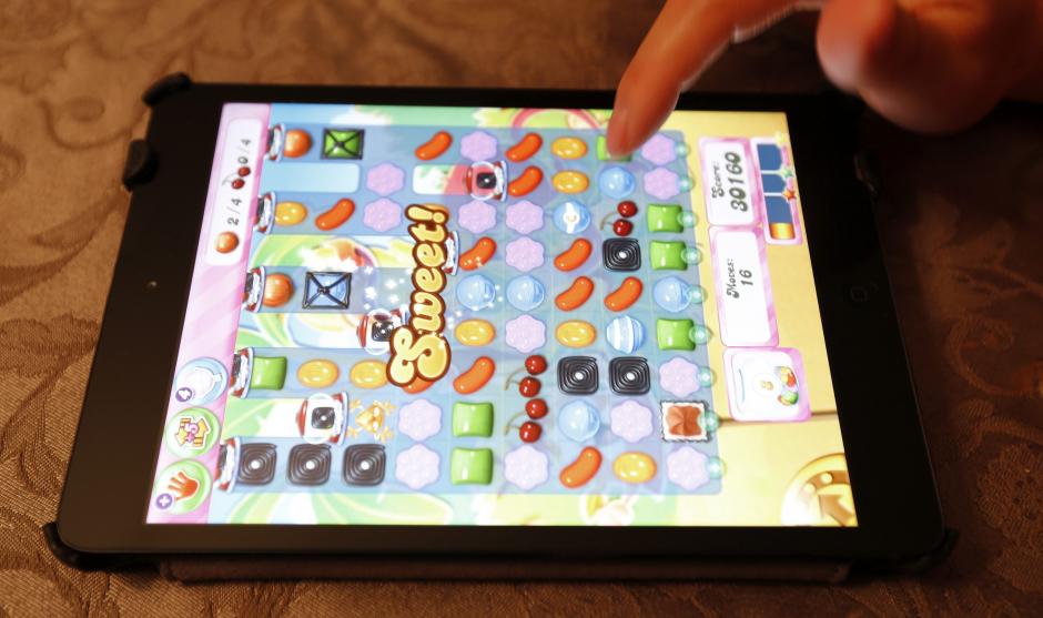 Una mujer juega al conocido videojuego online de King Digital Entertainment "Candy Crush Saga" en un iPad Mini en Norfolk. (Foto: EFE/Matt Campbell)
