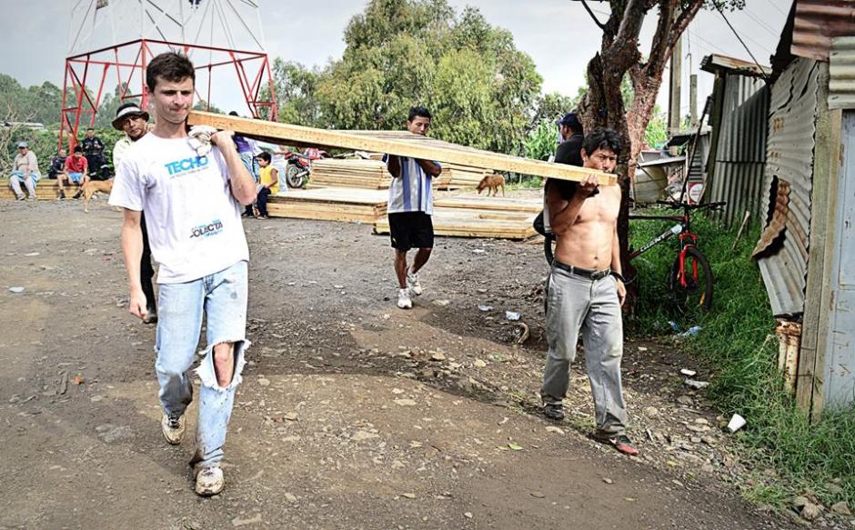Voluntario y vecinos colaboran durante las arduas tareas de descargue de materiales, previo a la construcción de viviendas. (Archivo TECHO).