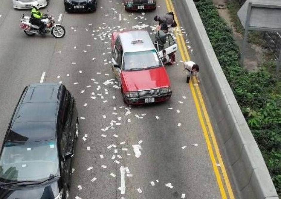 Varias personas detuvieron su camino para recoger los billetes que el camión blindado dejó a su paso por las calles de Hong Kong.