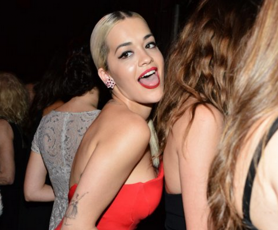 Rita Ora sonriendo pícaramente mientras hace una travesura.