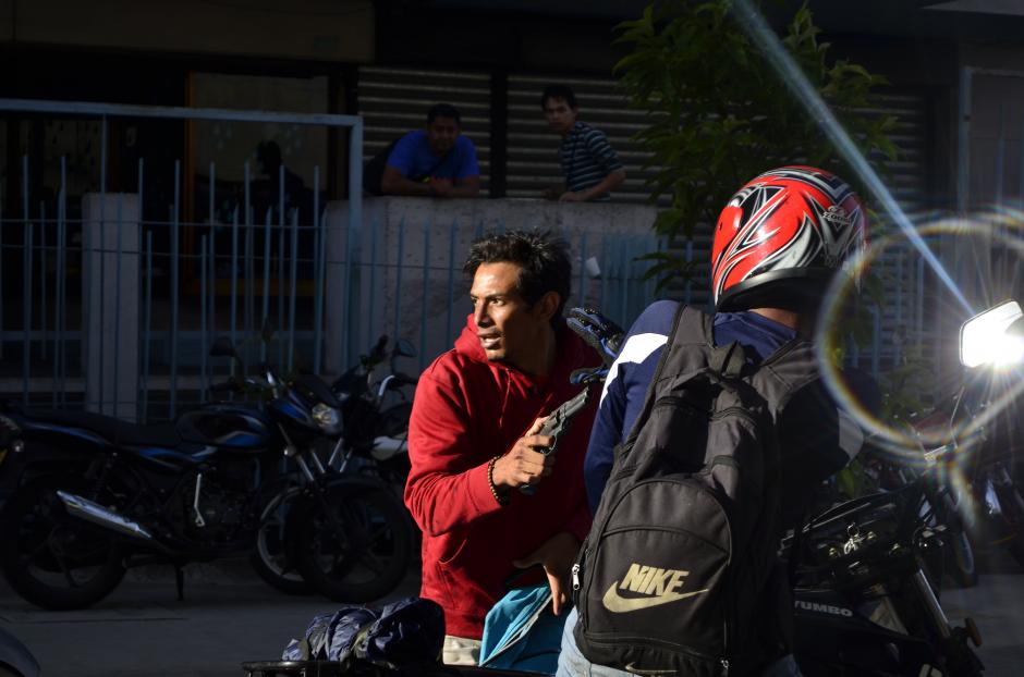 Este motorista reacciona con miedo ante el delincuente que lo amenaza con pistola. Esta imagen, captada por Deccio Serrano de Nuestro Diario en el Centro Histórico, muestra un momento en la huida de Armando Moisés Monzón Pereira, quien fue linchado por una turba luego de que despojara de su teléfono y le disparara a un estudiante del Colegio San Sebastián, el joven Leonel Alejandro Guillén Sosa. Ambos, estudiante y criminal, fallecieron como resultado de ese atraco.