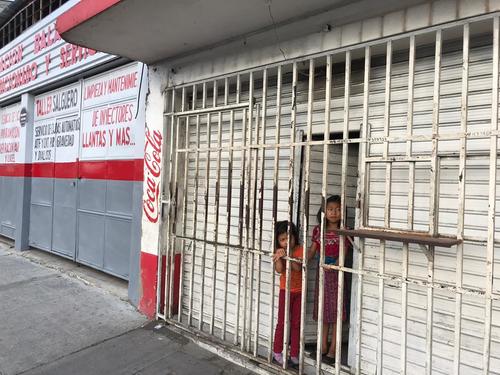 Dos niñas esperan que la tienda, donde viven, comience a atender a las personas. (Foto: Evelyn de León/Soy502) 