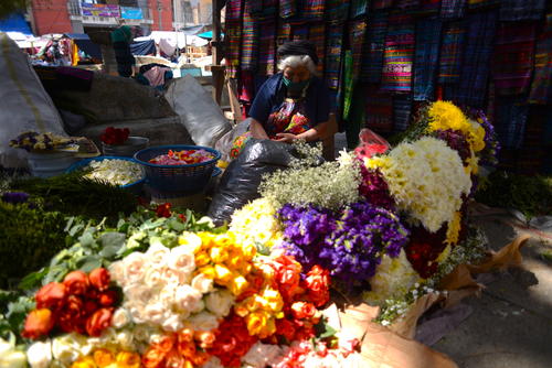 Una mujer vende flores en el día de mercado en Comalapa y utiliza las medidas de bioseguridad para atender a sus clientes. (Foto: Wilder López/Soy502)