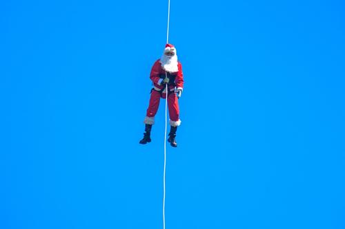 Santa Claus desciende varios metros a través de una cuerda ante la mirada sorpresiva de los pequeños. (Foto: AFP)