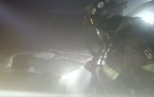 Uno de los bomberos intentando apagar el fuego en uno de los veh&iacute;culos. (Foto: captura de pantalla)