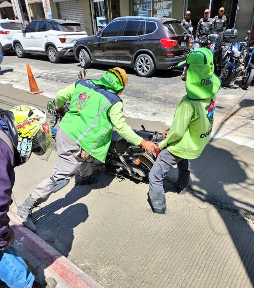 El motorista no pudo sacar su moto y tuvo que pedir ayuda de los trabajadores municipales. 