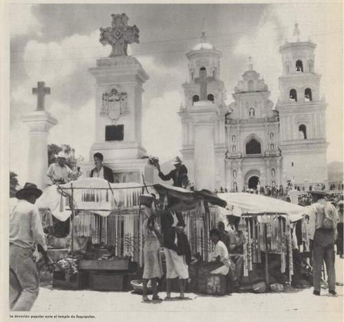 Fotografía de 1957 de comerciantes de artículos religiosos colocados frente a la entrada del templo. 
