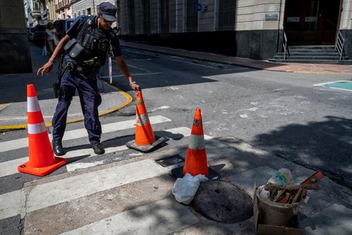 Un polic&iacute;a custodiando una alcantarilla en Montevideo. (Foto: AFP)