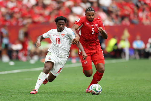 Jonathan David disputando un bal&oacute;n con el central suizo, Manuel Akanji. (Foto: AFP)