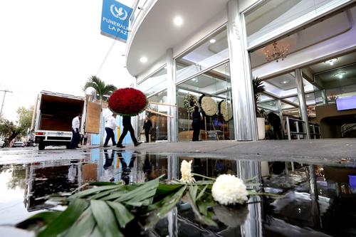 Empleados descargan un arreglo floral afuera de la funeraria. (Foto: AFP)