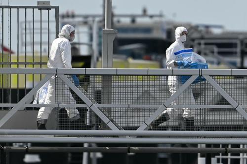Varias personas con trajes de protecci&oacute;n contra materiales peligrosos abandonan el crucero tras su llegada al puerto de Rotterdam (Foto: AFP)