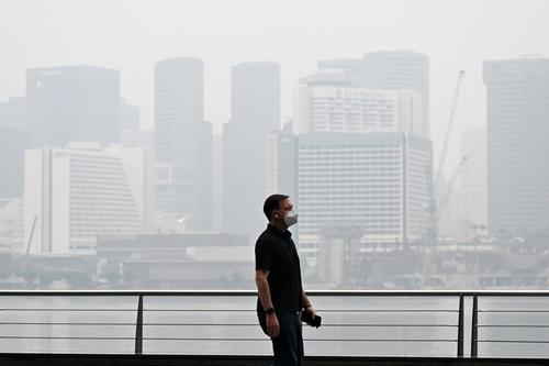 Un hombre se cubre con mascarilla para evitar que el humo cause da&ntilde;os en su sistema respiratorio. (Foto: AFP) 