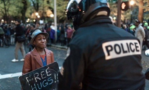 Devonte Hart sostiene un letrero de "abrazos gratis" ante el oficial Bret Barnum. (Foto: Twitter)