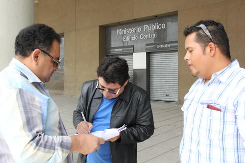 Álvaro Velásquez firma la denuncia frente al edificio del Ministerio Público acompañado de su abogado.  (Foto: Antonio Ordoñez/Soy502)