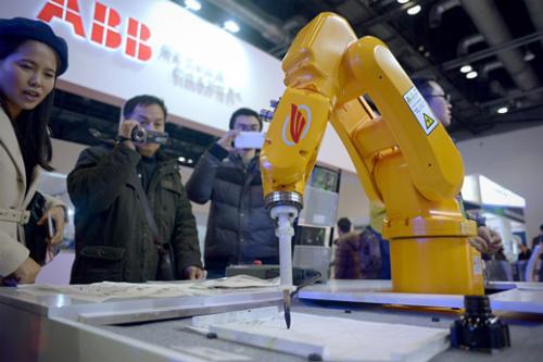 Foto de archivo de la Conferencia Mundial de Robot en Beijing, los asistentes ven un robot industrial escribir. (Foto: technologyreview)