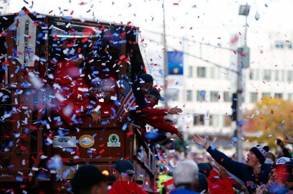 Aficionados estrechan las manos de los peloteros druante el desfile de celebraci&oacute;n de las Medias Rojas de Boston, tras ganar la Serie Mundial ante Los Cardenales de San Luis. ( Jared Wickerham/AFP)