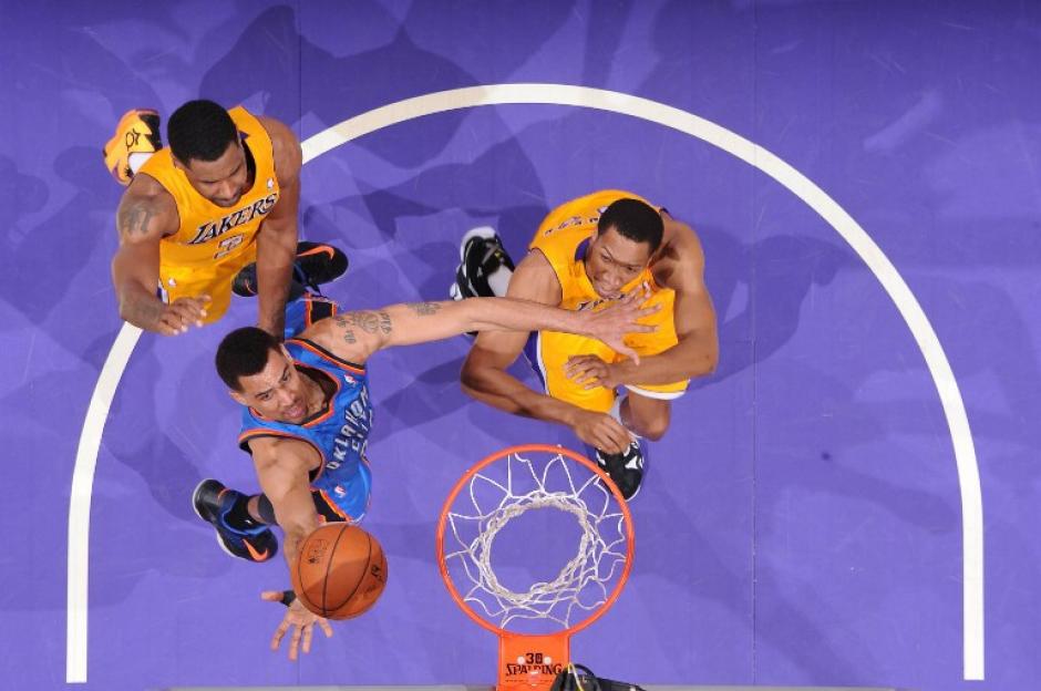 Thabo Sefolosha de los Thunder de Oklahoma City, realiza un tiro ante Shawne Williams &nbsp;y Wesley Johnson de los Lakers. (Foto: Andrew D. Bernstein/AFP)