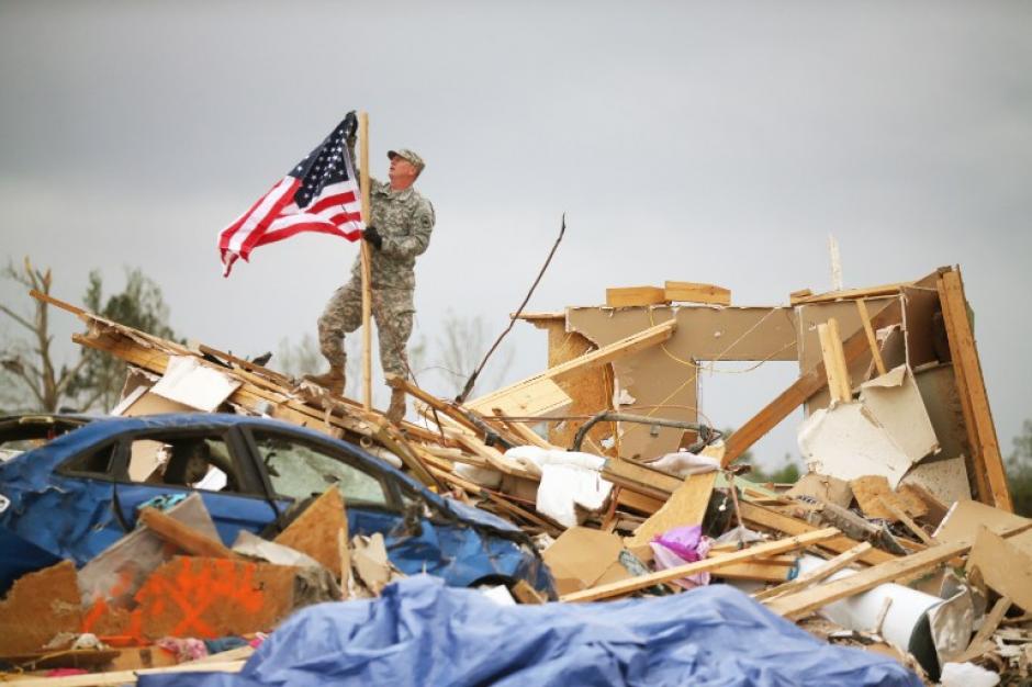 El sargento de la Guardia Nacional de Arkansas, Skipper Smith cuelga una bandera americana en una casa que &nbsp;detruida cuando un tornado azot&oacute; la zona de Vilonia, Arkansas. Los tornados azotaron la regi&oacute;n 27 de abril, dejando a m&aacute;s de una docena de muertos. (Foto: Mark Wilson / AFP)