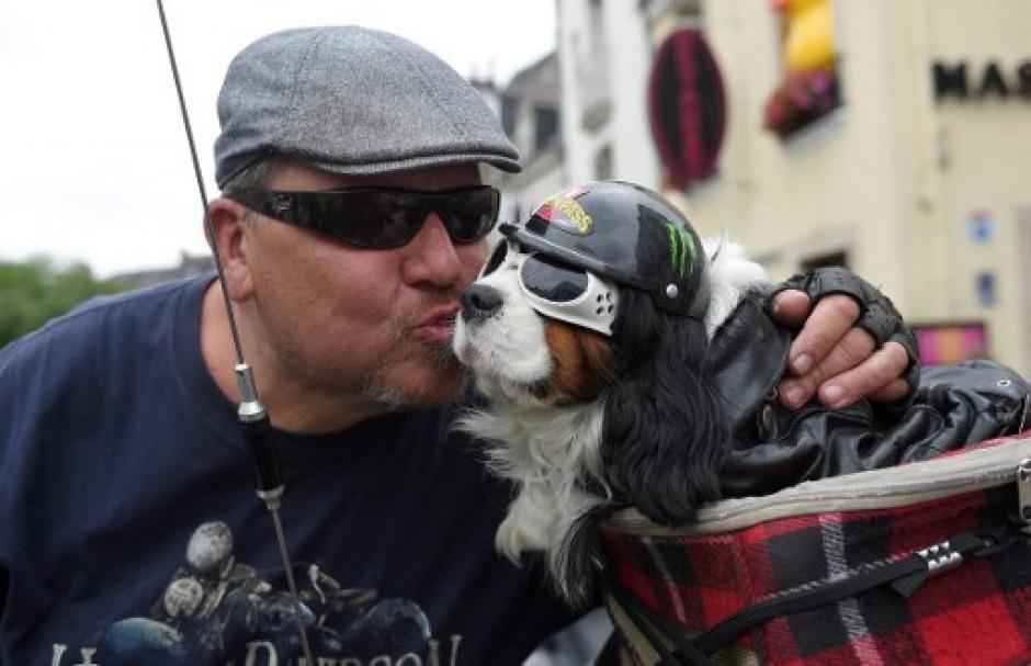 Un hombre le da un beso a su mascota previo a partir en la caravana del desfile motorizado. (Foto: Guillaume Souvant/AFP)