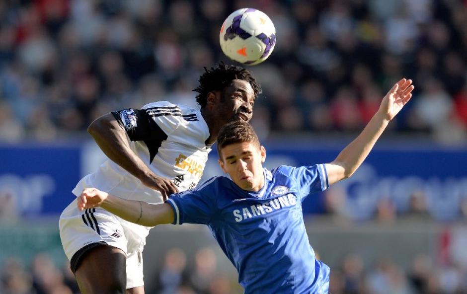 El medio campista brasile&ntilde;o del Chelsea, Oscar, salta para quitar la pelota a Wilfried Bony del Swansea. (Foto: AFP)&nbsp;