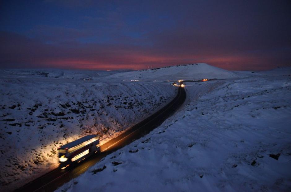 Un bus de dos niveles recorre un camino cubierto por nieve, en la villa de Diggle, Reino Unido. (Foto: Oli Scarff/AFP)