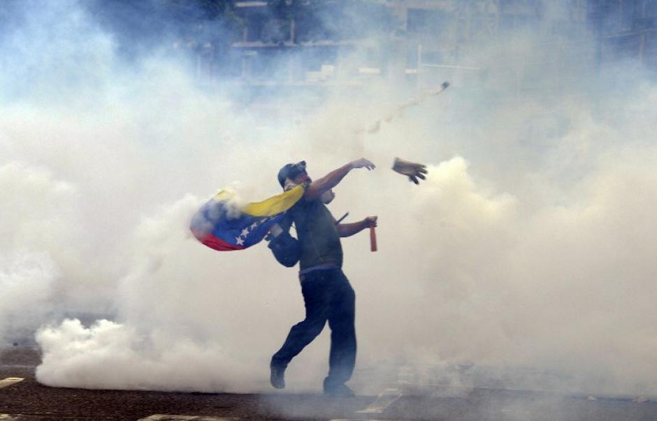 Un manifestante lanza piedras a los polic&iacute;as antidisturbios durante una protesta contra el gobierno en el este de Caracas. Duelo de manifestantes a favor y en contra del gobierno han estado tomando a las calles desde el 4 de febrero en un signo de la profunda polarizaci&oacute;n. (Foto: AFP/Juan Barreto)